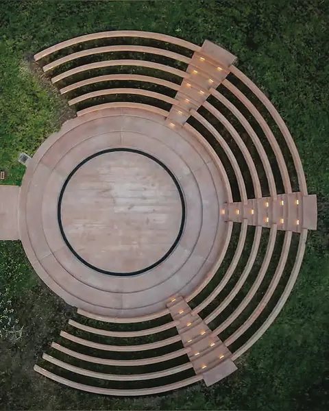 Top-down view of a circular stepped amphitheatre with timber seating