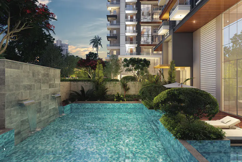 Swimming pool with a stone water wall, lush planting and the tower behind at dusk